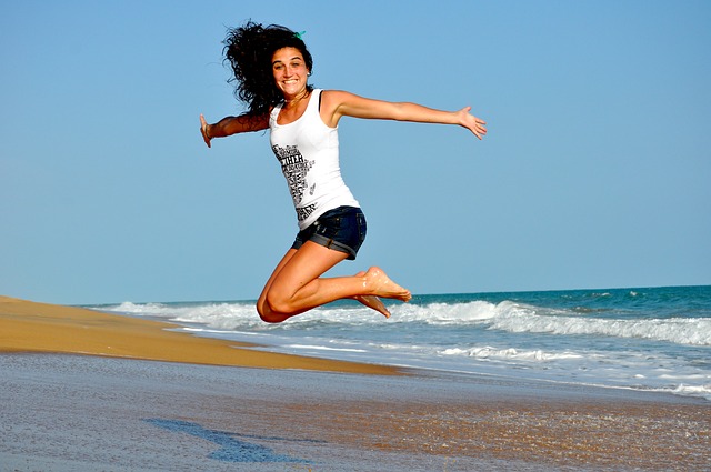 woman jumping for joy at beach