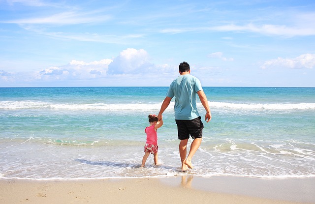 dad walking on beach with daughter