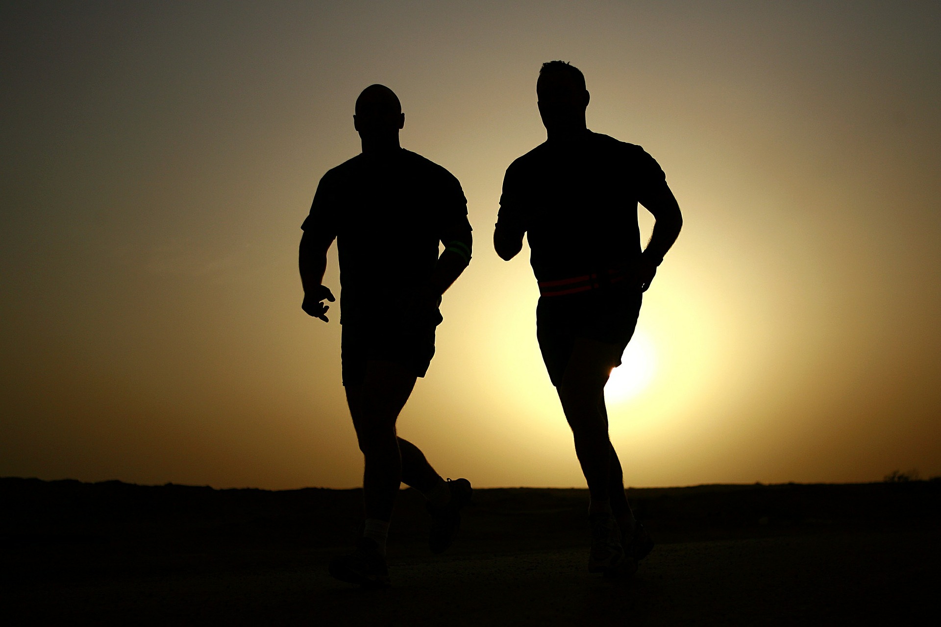 silhouette of two men jogging during sunset